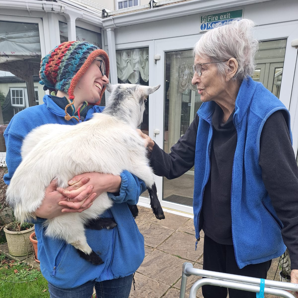 Woman stood holding and looking at a goat