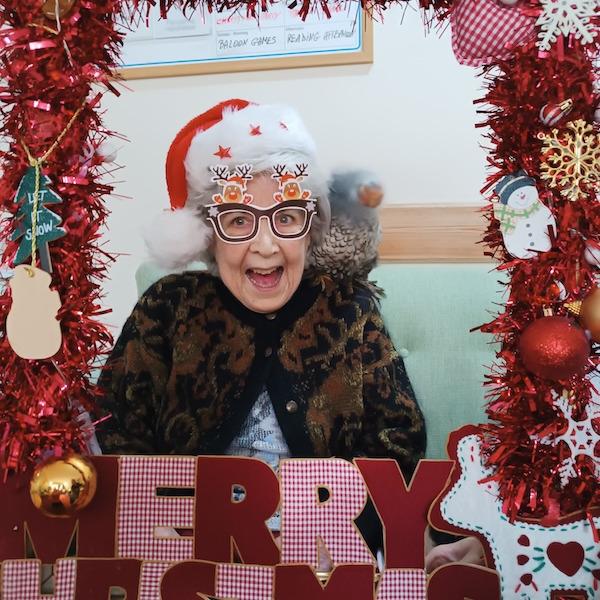 An elderly lady smiling, dressed up for a Christmas party