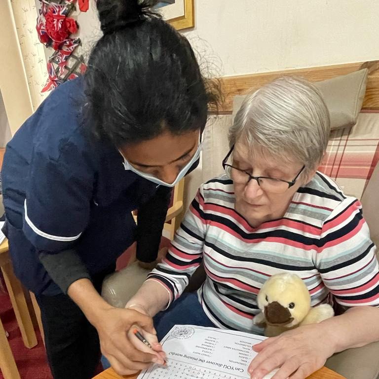 A staff member helping a resident with a word puzzle