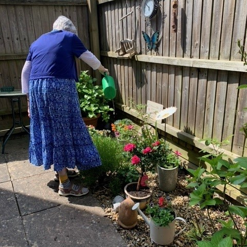 Elderly lady watering flowers in the garden
