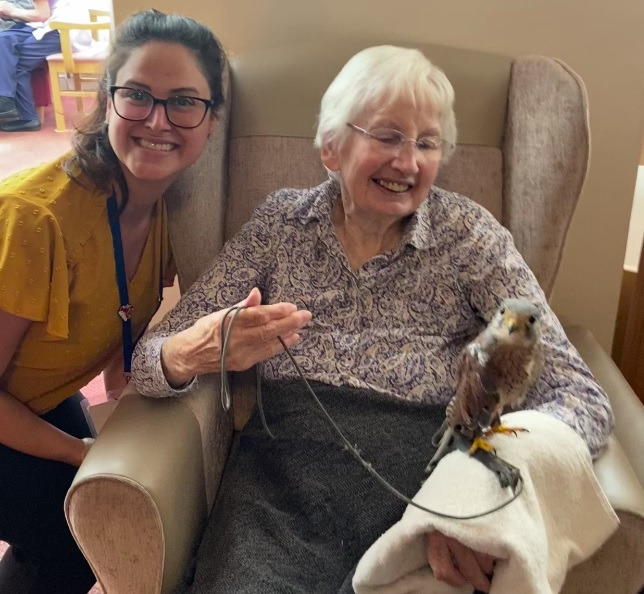 A staff member and resident smiling, looking at a bird