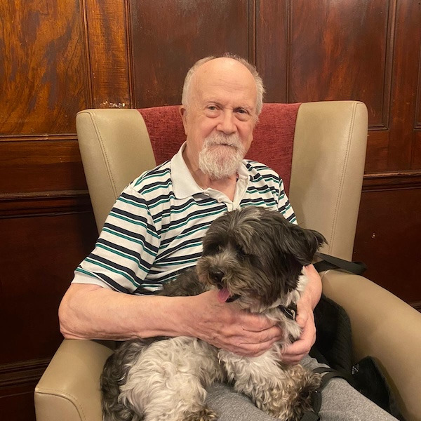 An elderly gentleman sat with a dog