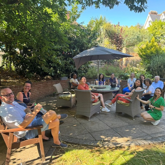 A group of smiling people sat on garden furniture outside 