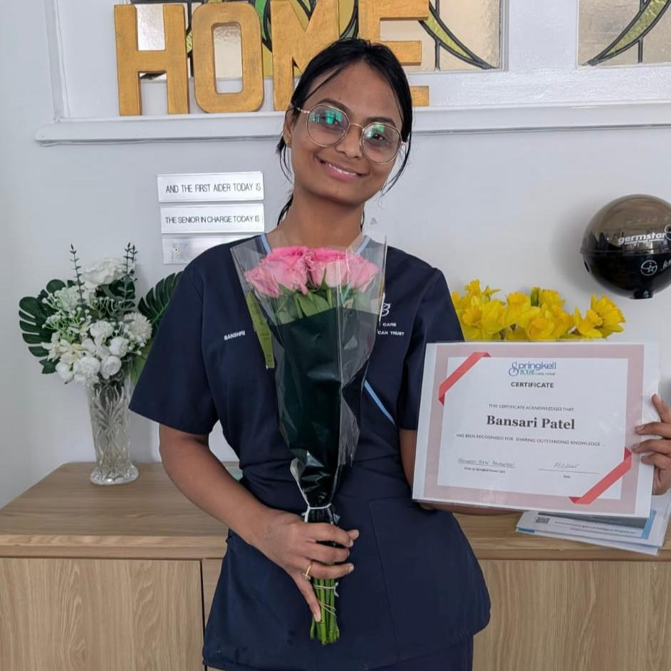 Team member holding a certificate and flowers