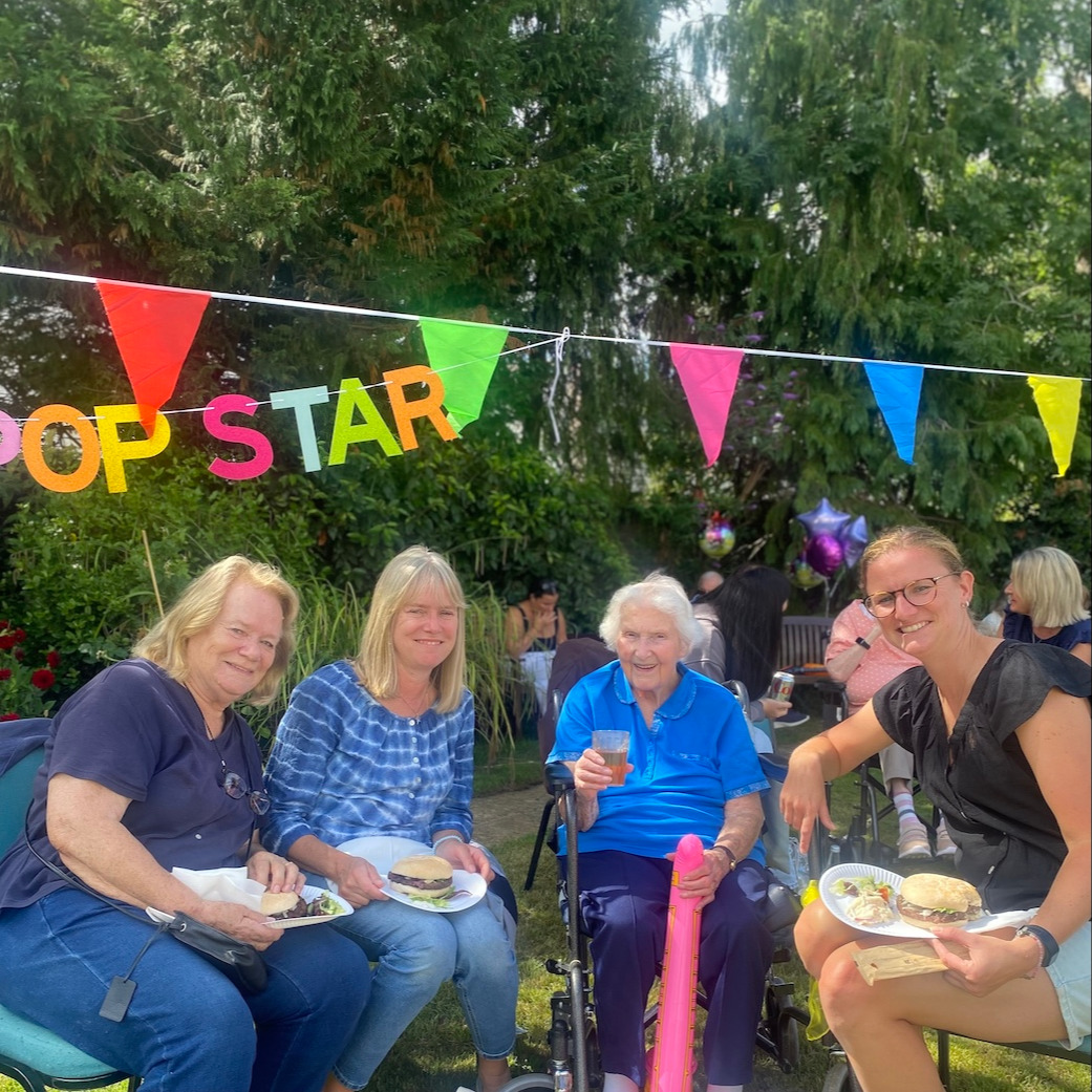  A family smiling while eating party food at an outdoor garden party