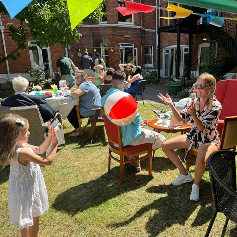 People and children playing ball games at a summer garden party