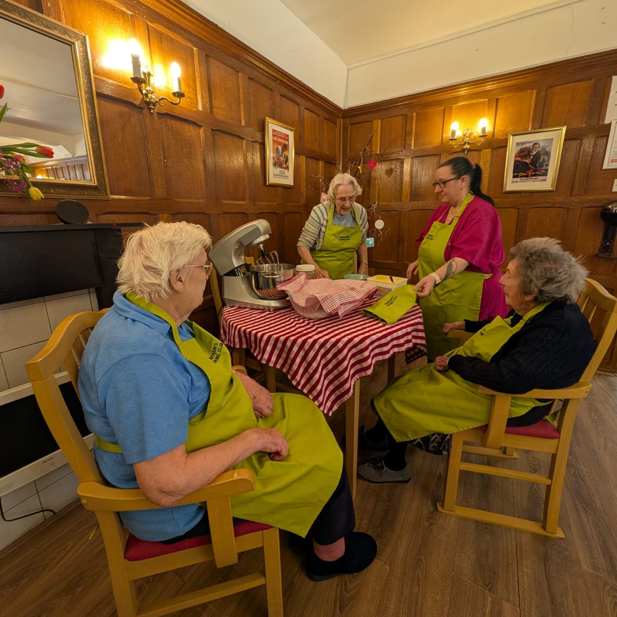 A group of people sat around a table baking a cake