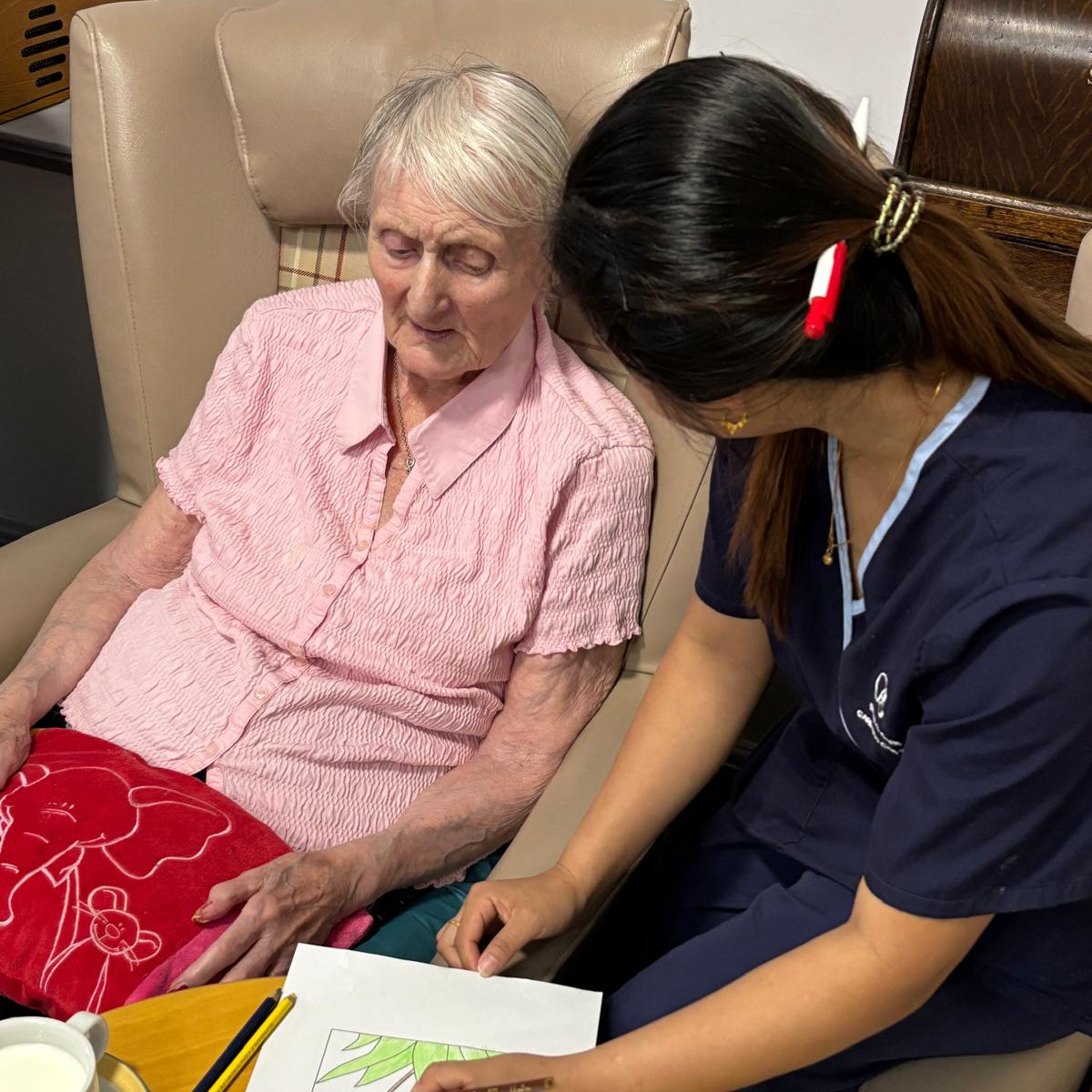 A staff member doing an art activity with an elderly woman