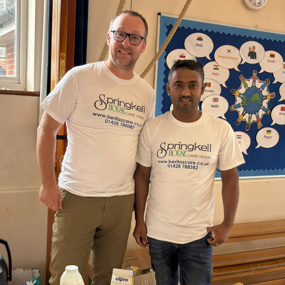 Two men stood in front of a cake stall wearing branded tshirts