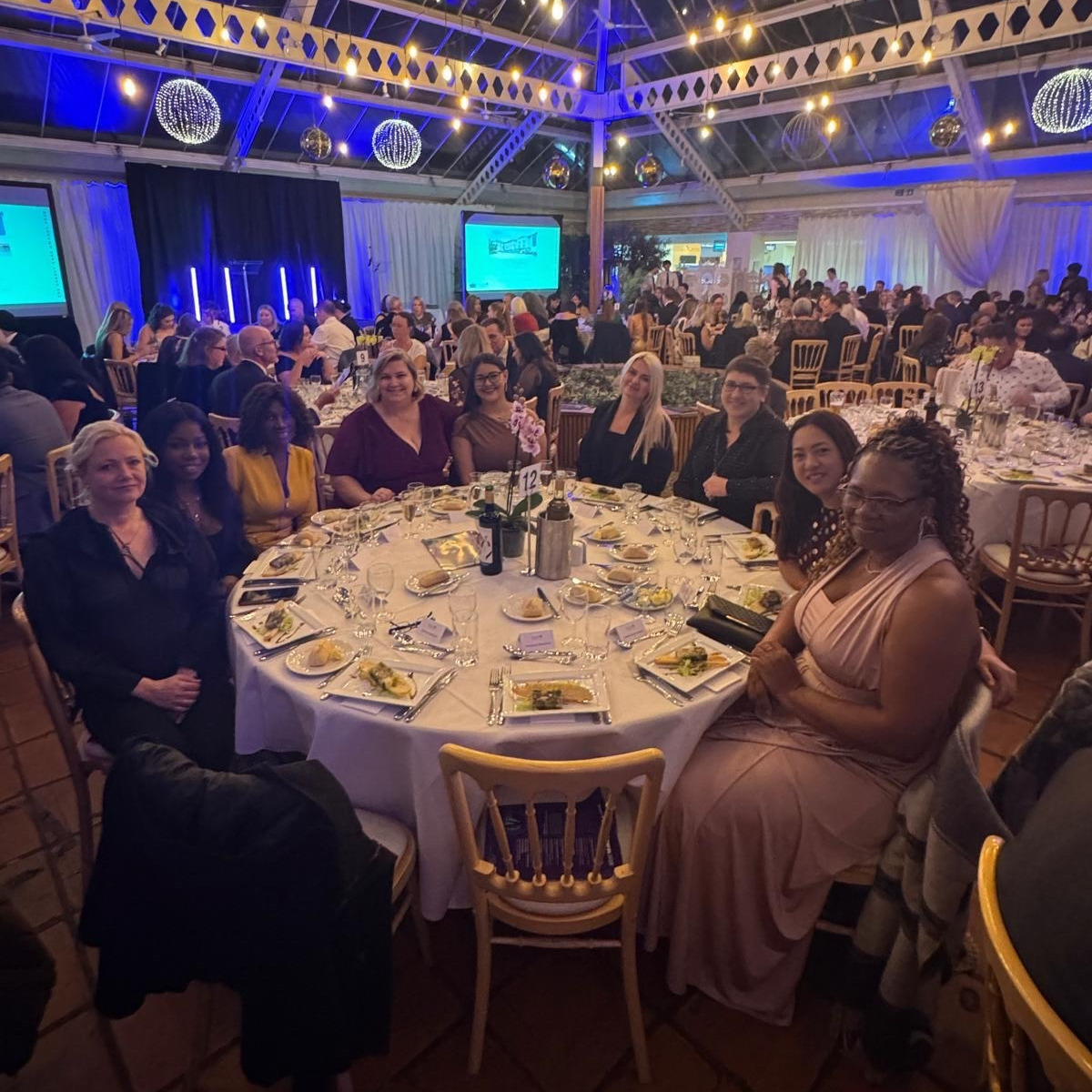 People in formal wear sat at a table at an awards events