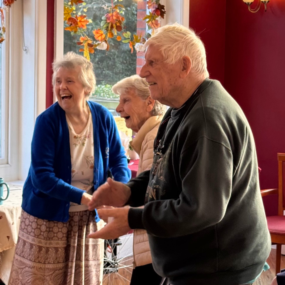 A group of elderly people smiling and dancing to musical entertainment