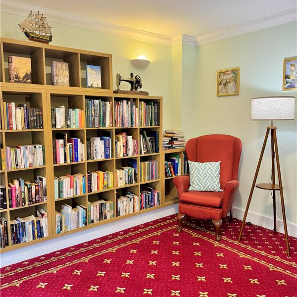 A library room with bookshelves, a chair and lamps.
