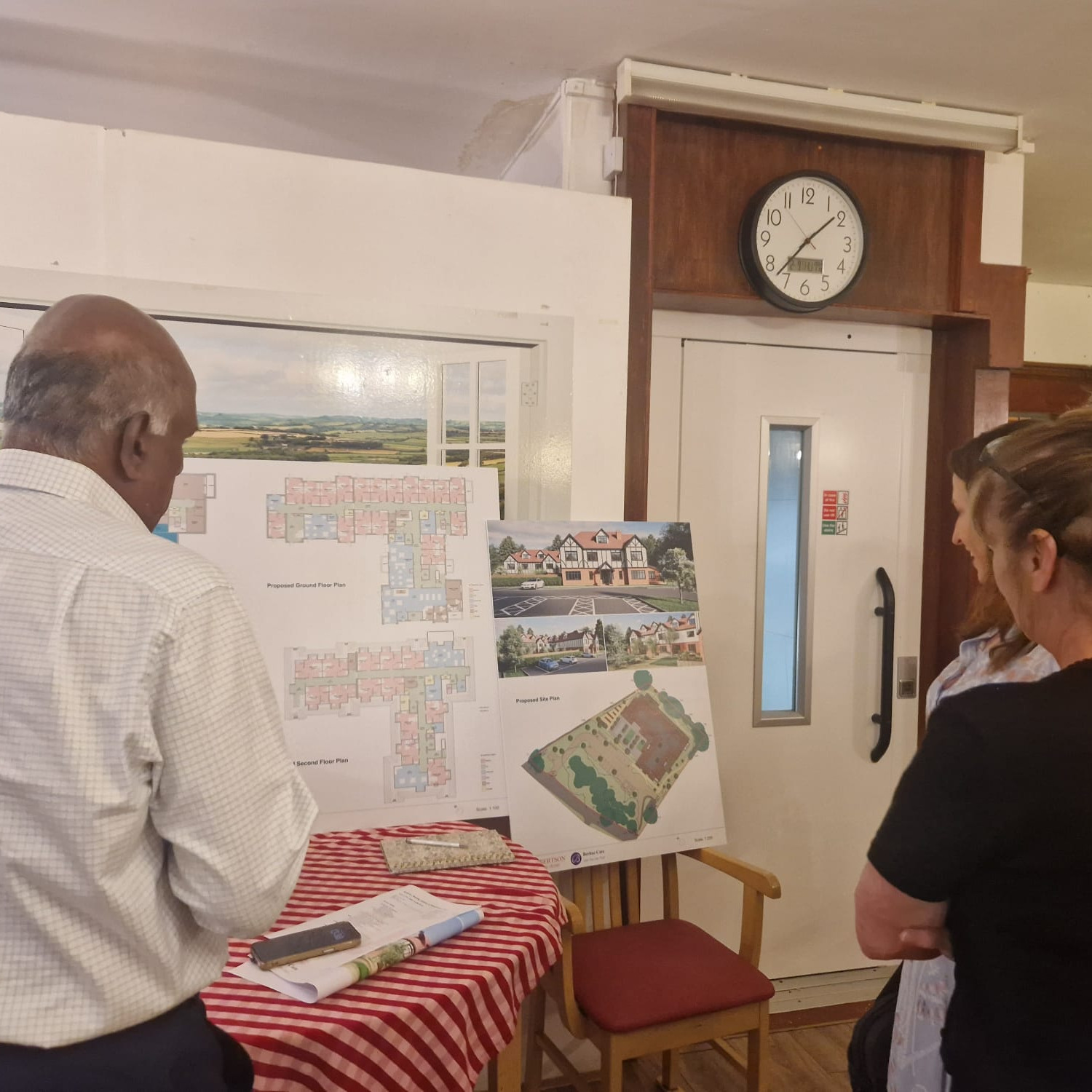 People looking at plans on a notice board for a new building 