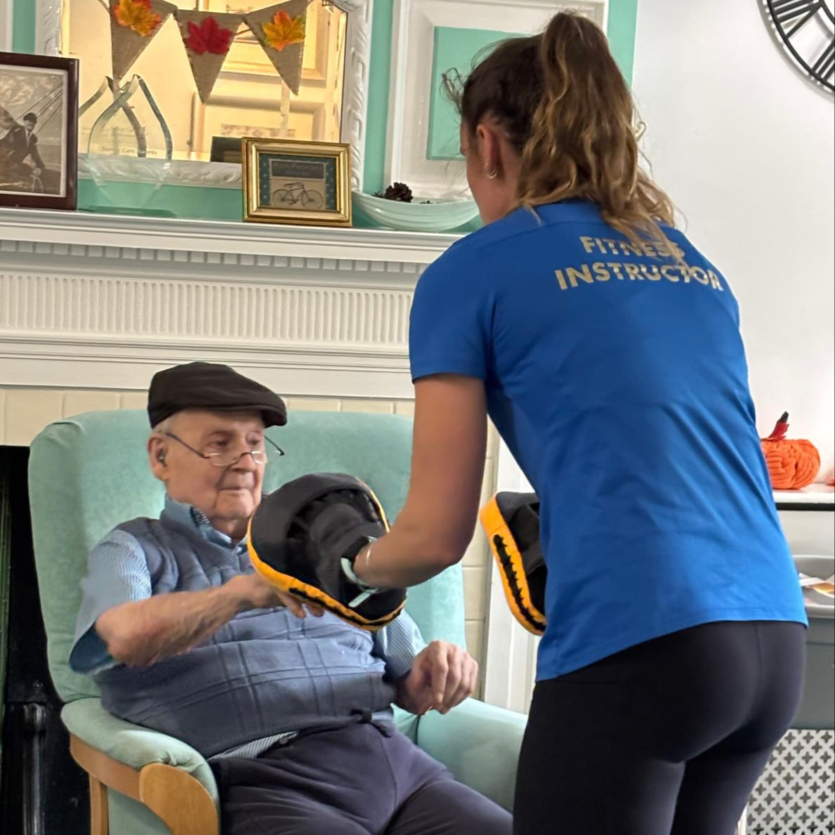 An elderly man taking part in armchair exercises with a fitness instructor