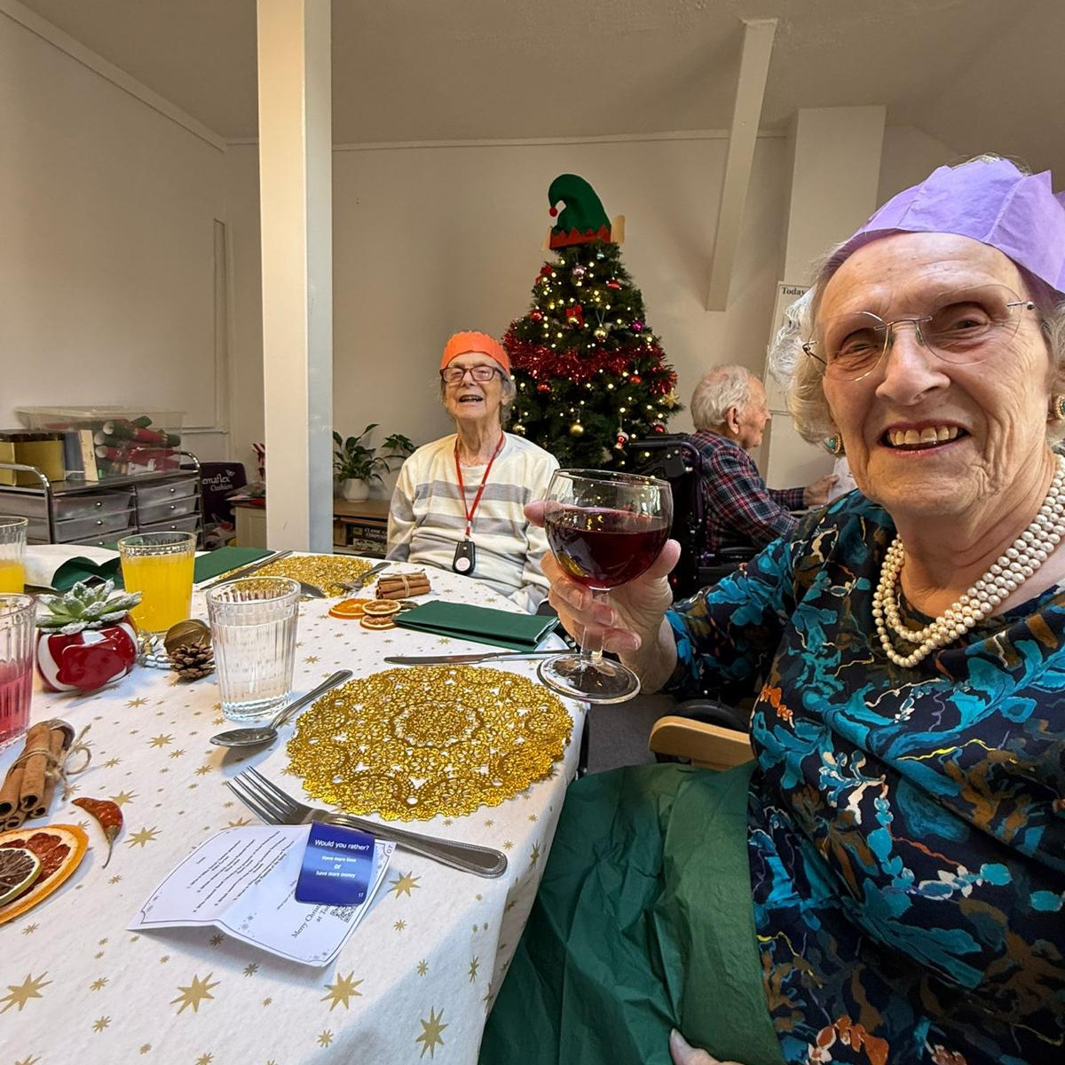People at a dining table before Christmas lunch and a lady toasting with a wine glass