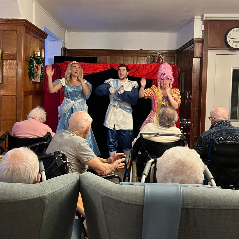 Performers putting on a pantomime in front of an audience at a care home