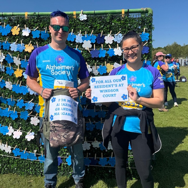 Two people smiling and holding up signs after comleting a sponsored walk