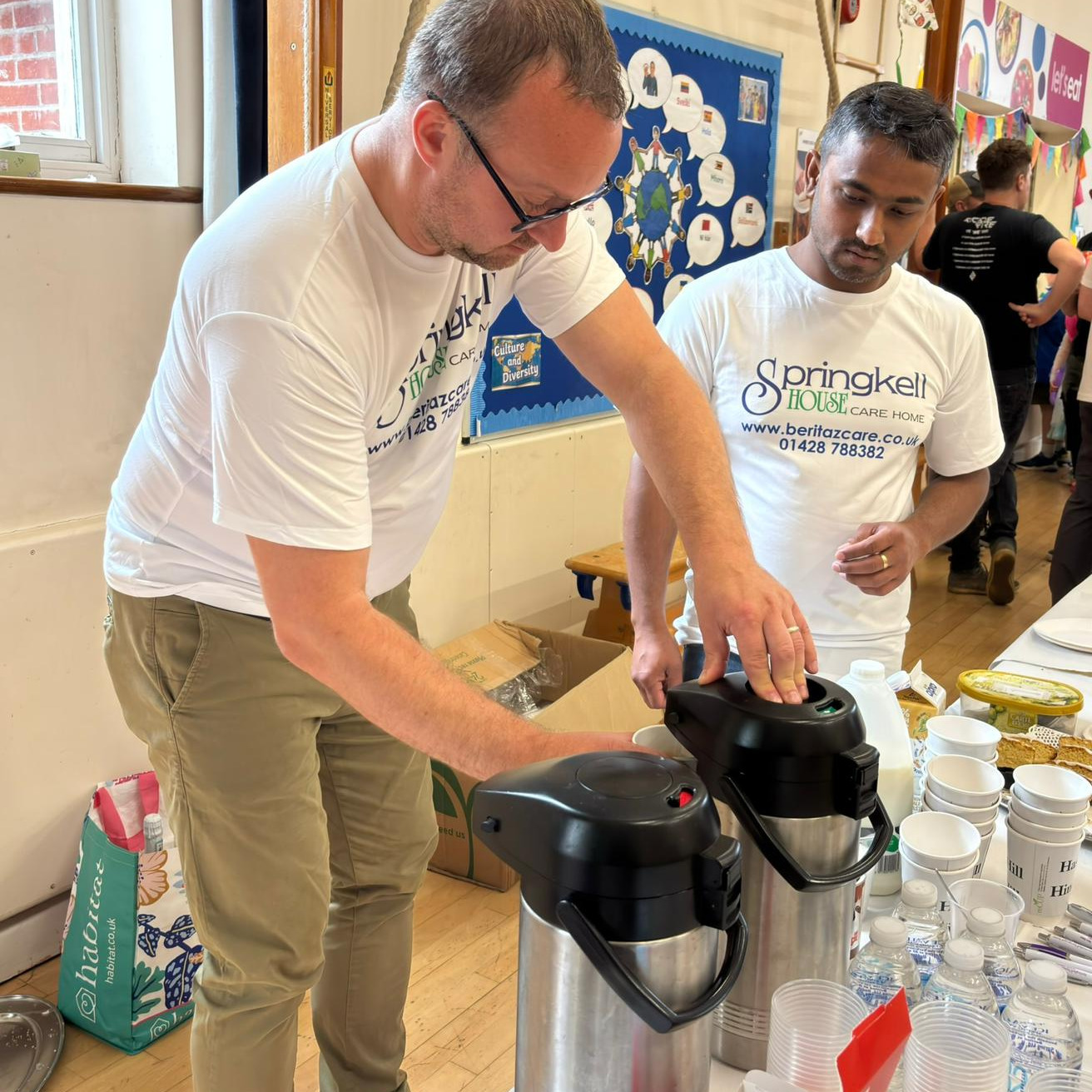 Two volunteers serving tea and coffee at a community event