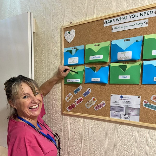 A woman smiling while taking a note from a notice board talking about mental health