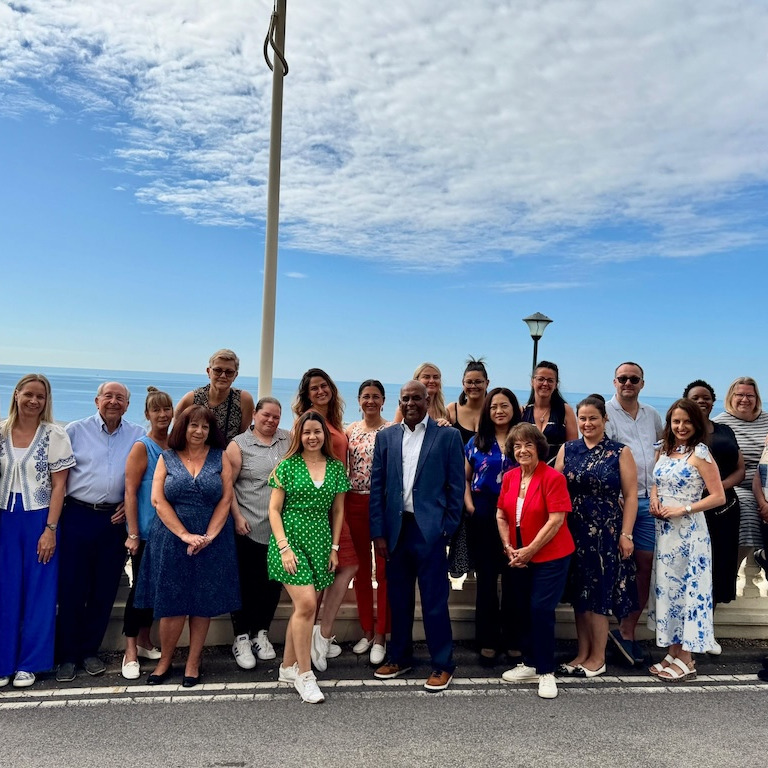 A large group of people stood outside in front of the sea