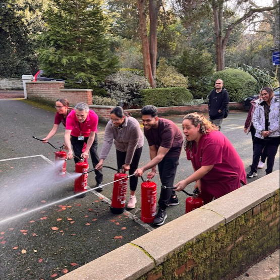A group of staff using fire extinguishers during fire safety training
