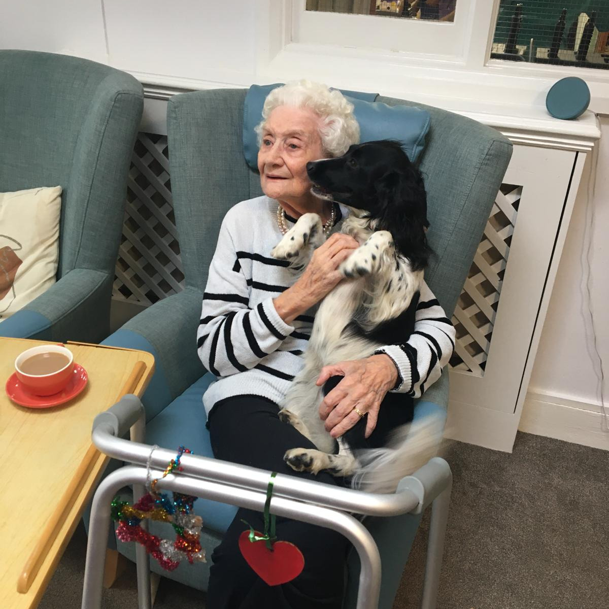 An elderly lady cuddling a puppy
