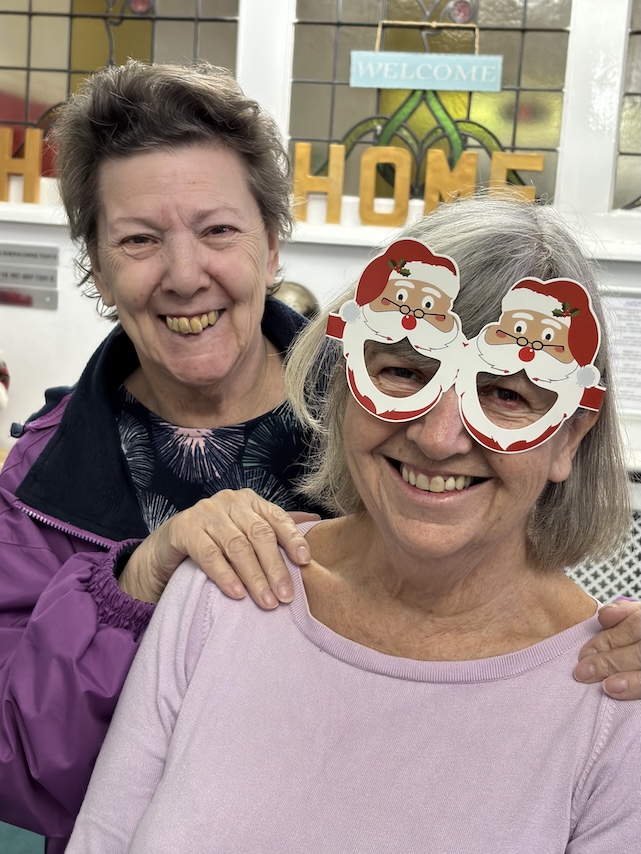 Two smiling ladies, one wearing novelty Christmas glasses