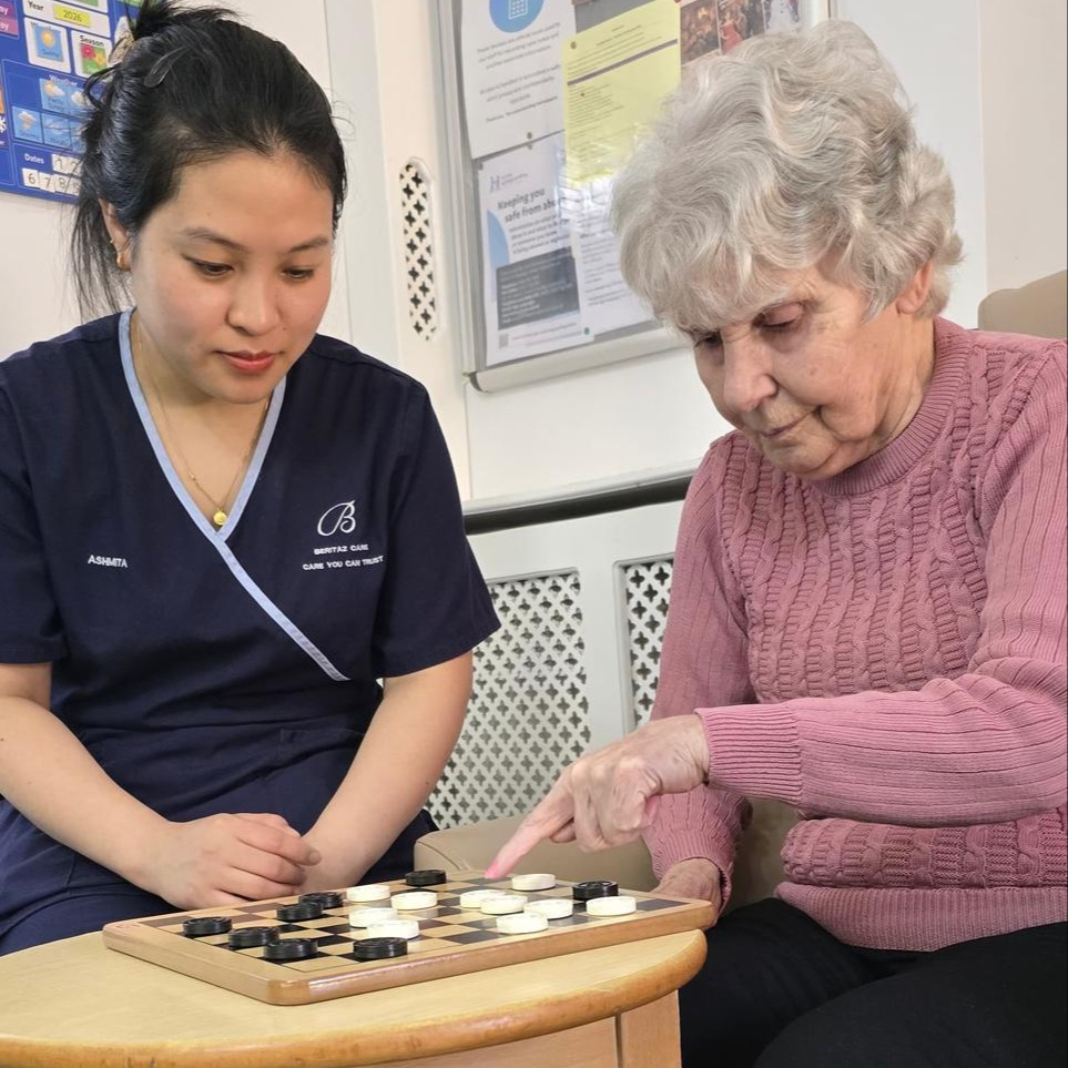 An older lady and staff member playing a board game