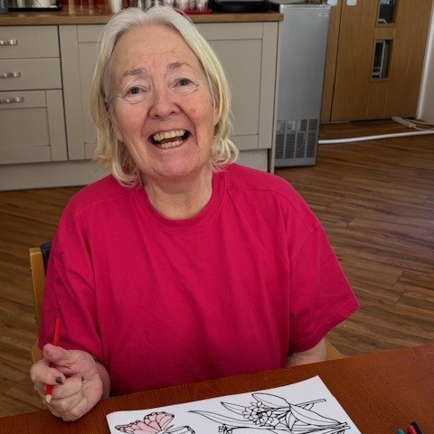 A lady smiling while doing arts and crafts