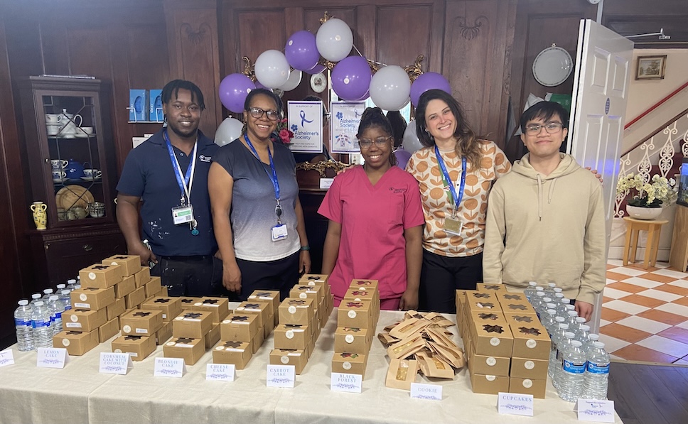 A group of people stood at a cake sale table