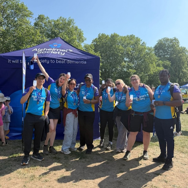 A large group of people stood outside having completed a sponsored walk