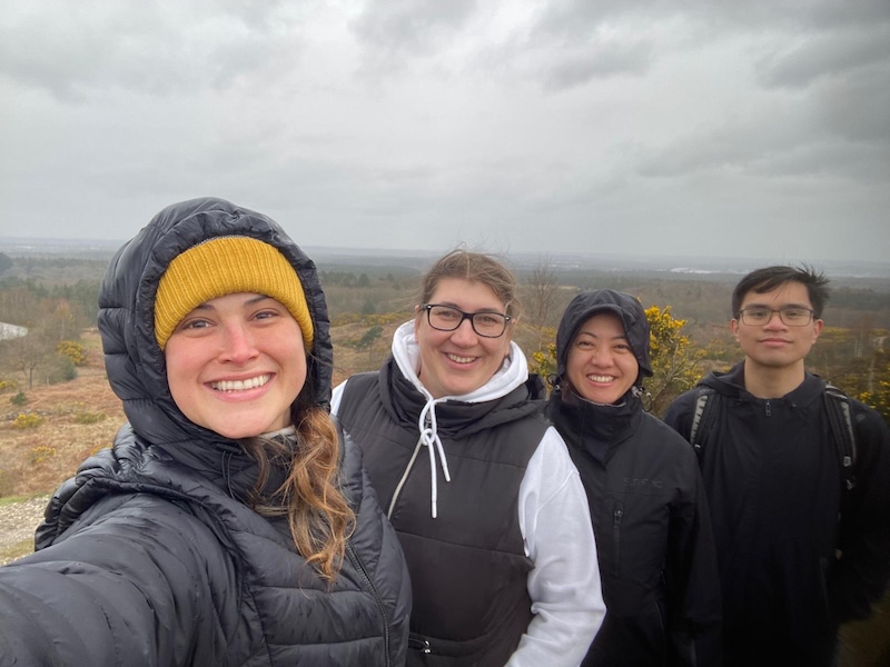 A group of people on a walk in front of a cloudy landscape