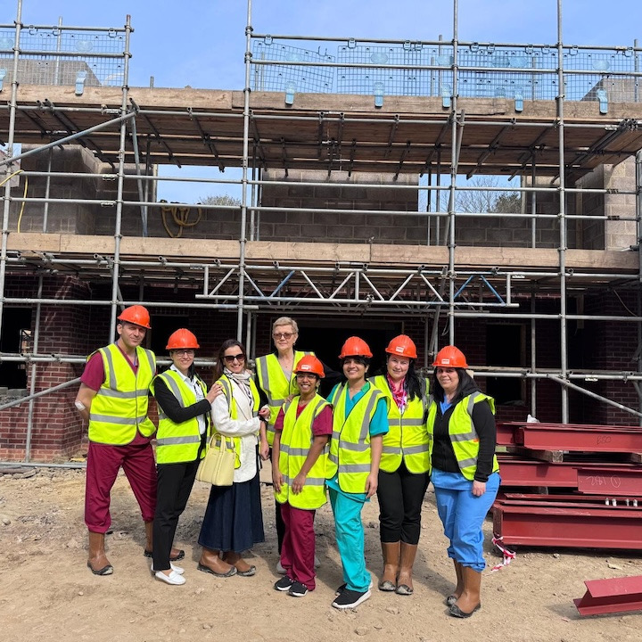 A group of people in hard hats and high-vis vests stood in front of a construction site