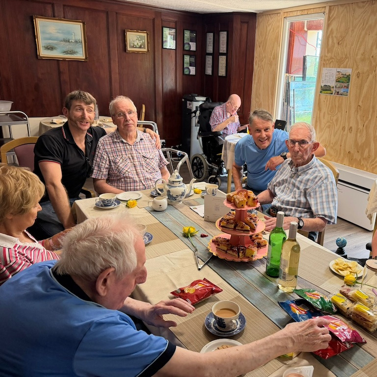 A group of people sat around a table enjoying afternoon tea