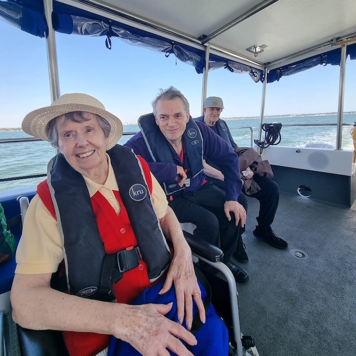 People with life jackets sat on a boat