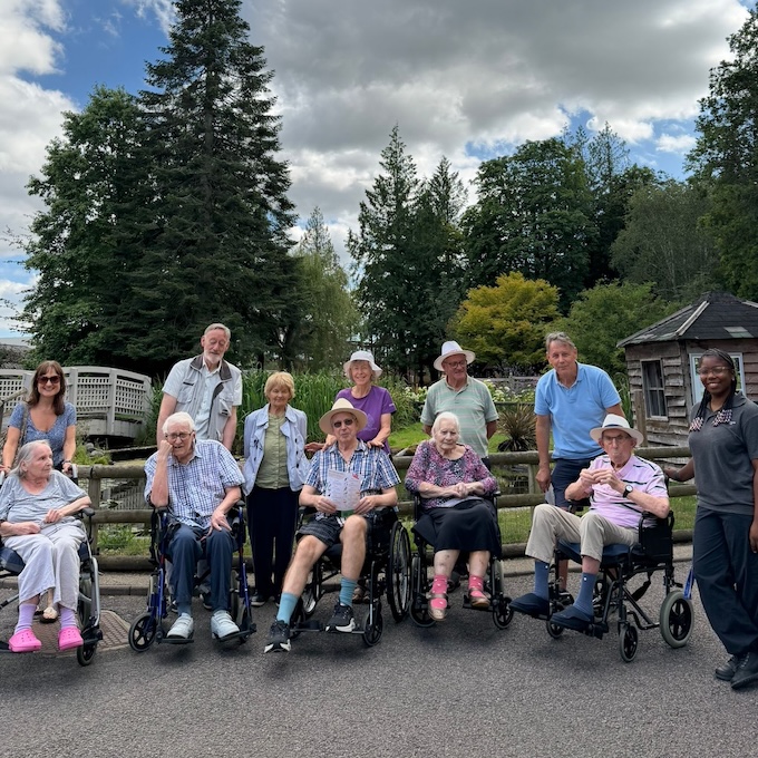 A group of people some in wheelchairs in front of a tree line