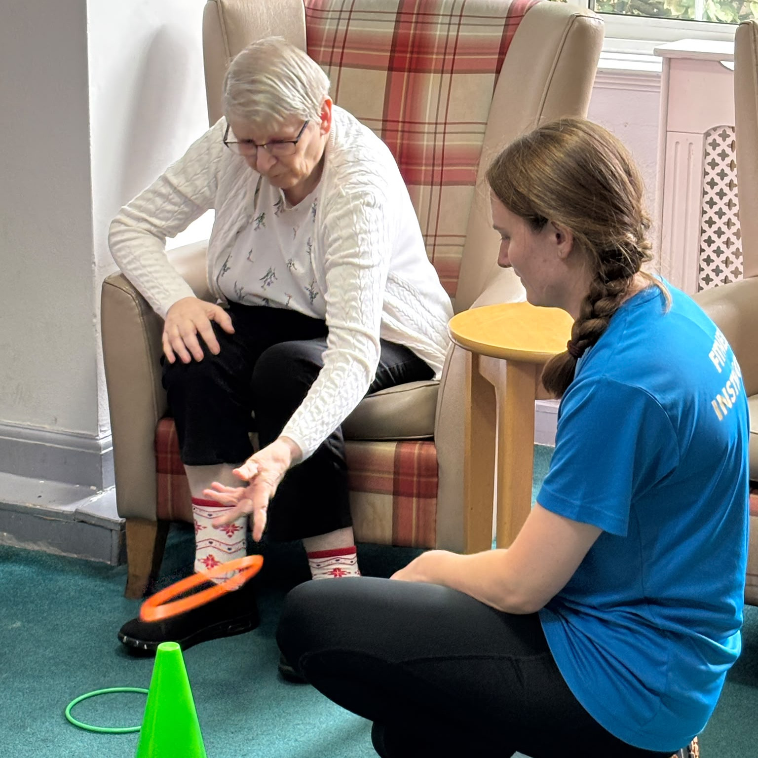A staff member helping an older woman with an exercise game