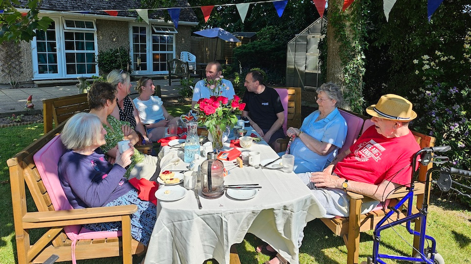 A group of people enjoying a tea party outside in the sunshine