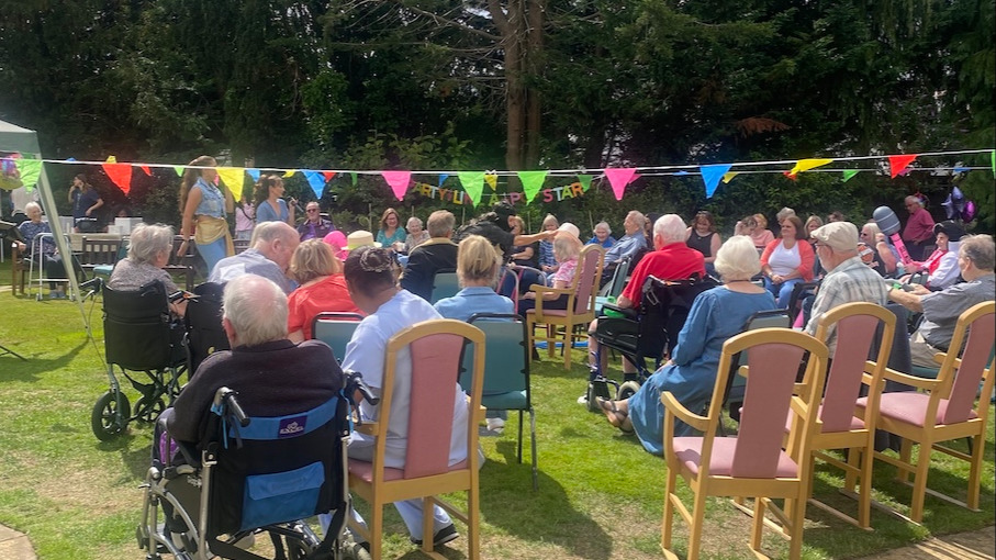 A group of people enjoying a garden party outside in the sunshine