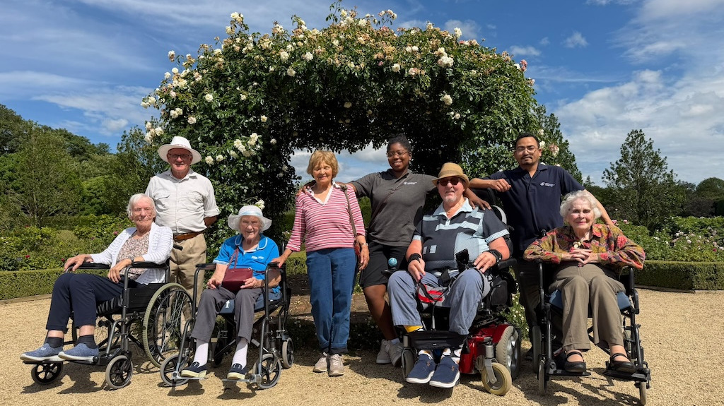 A group of people stood in a garden in front of a floral archway