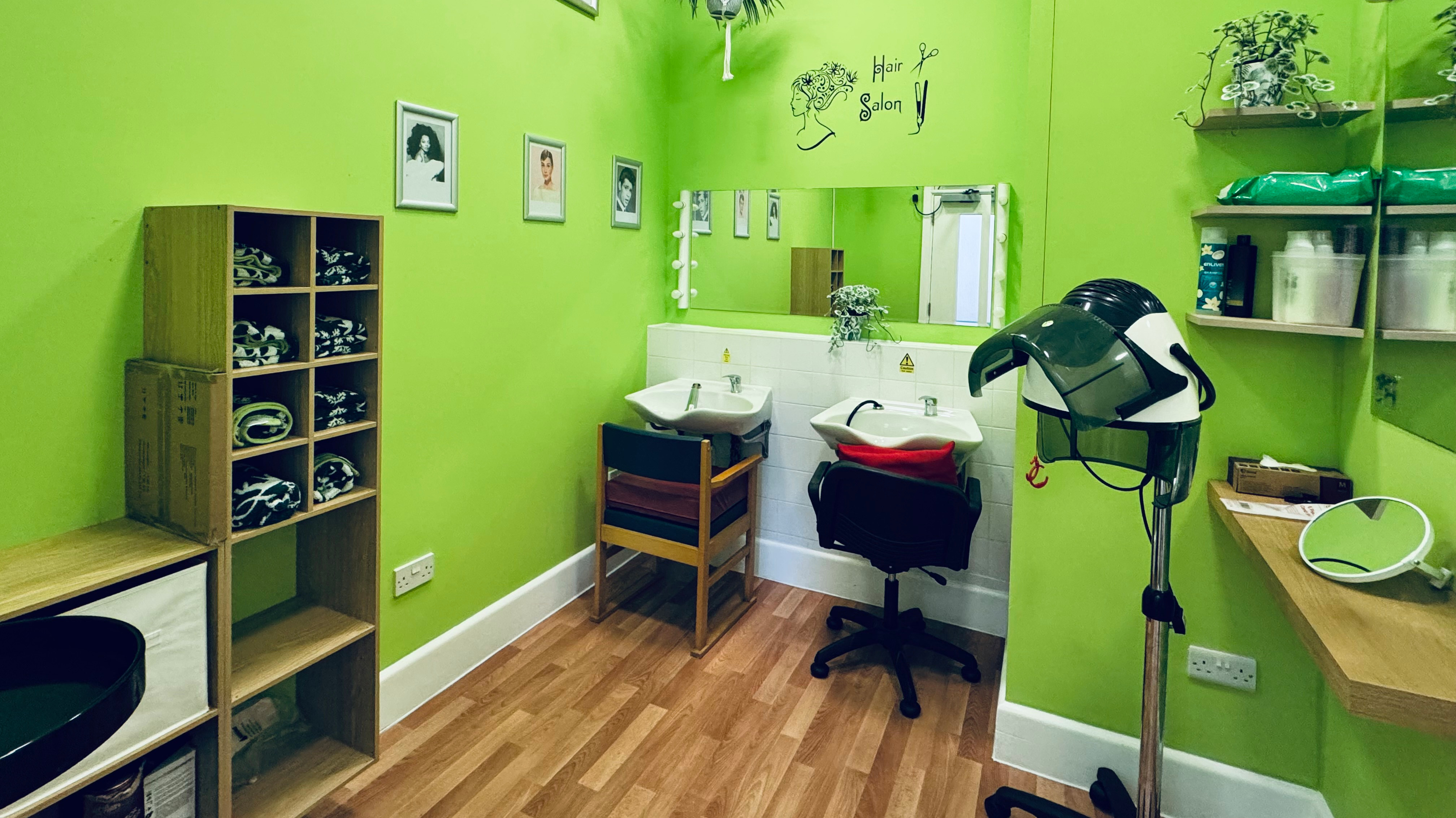 A clean salon with two sinks for washing hair a curling station. There are mirrors on the wall and the room is brightly decorated. 