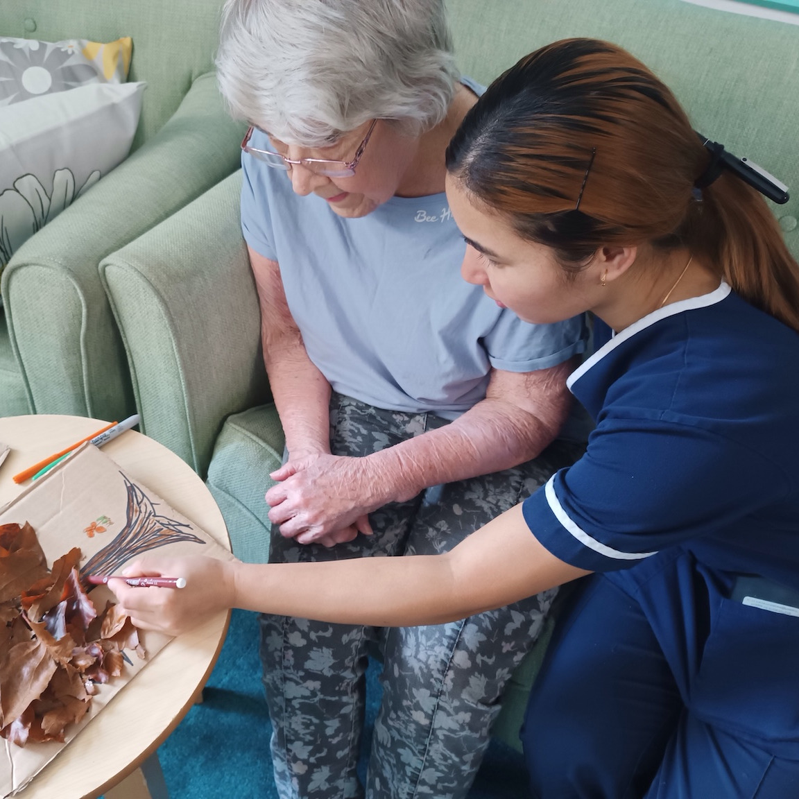 Springkell staff member sat doing an activity with a resident