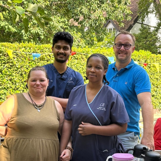 A group of staff members serving refreshments at the summer garden party
