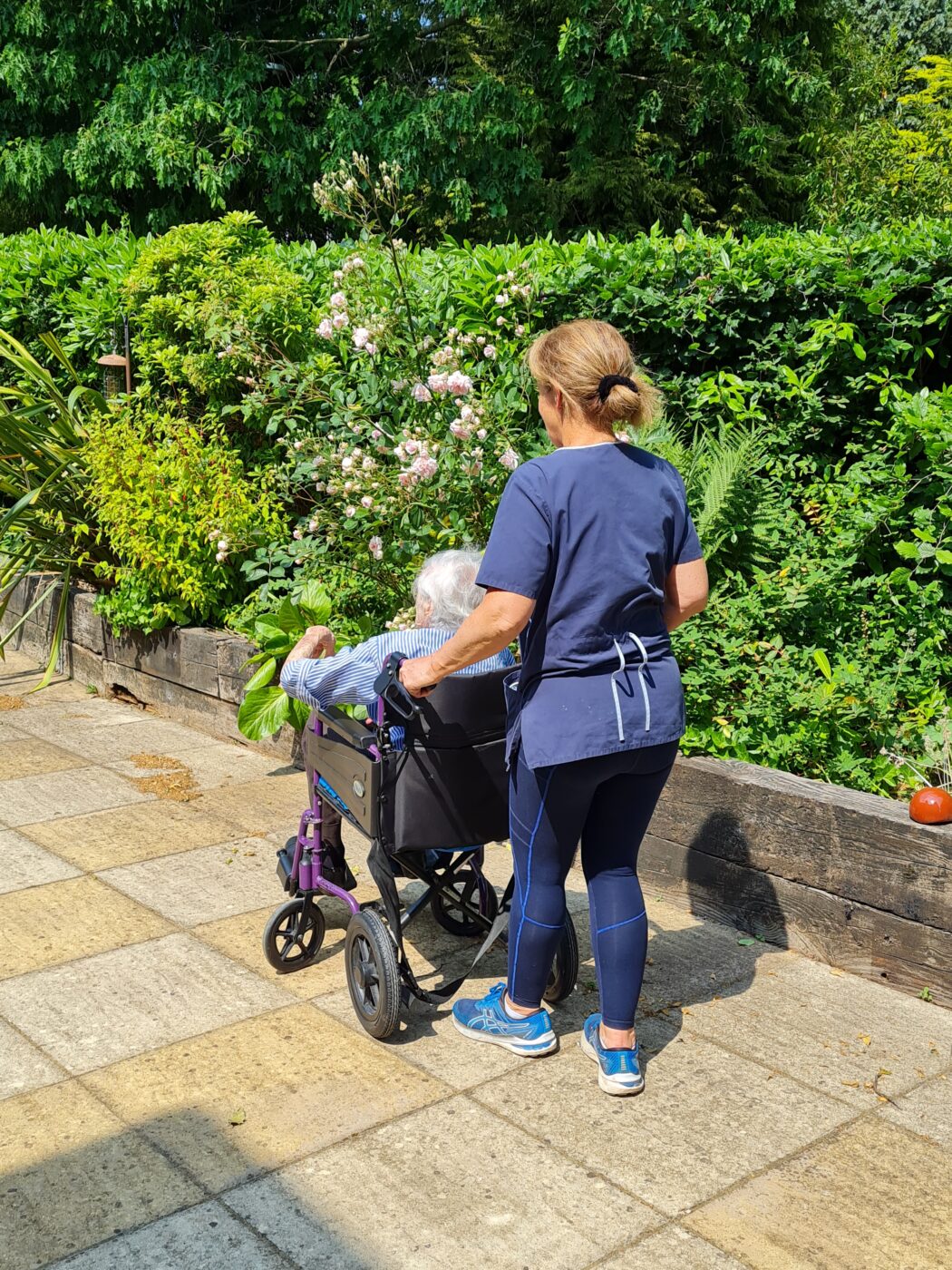 A care assistant taking a walk with a woman in a wheelchair