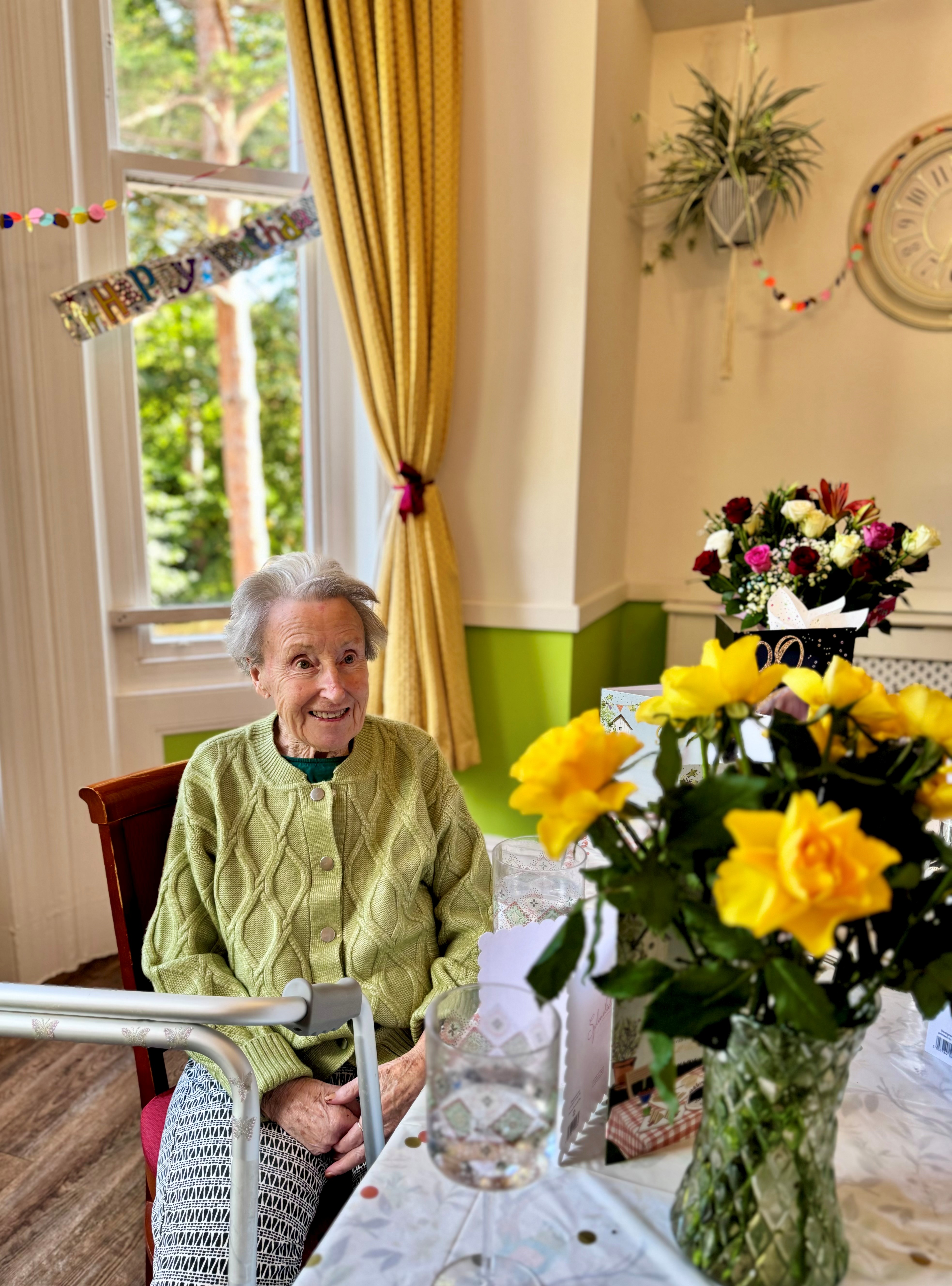 A woman looking at some pretty flowers with a birthday banner in the background