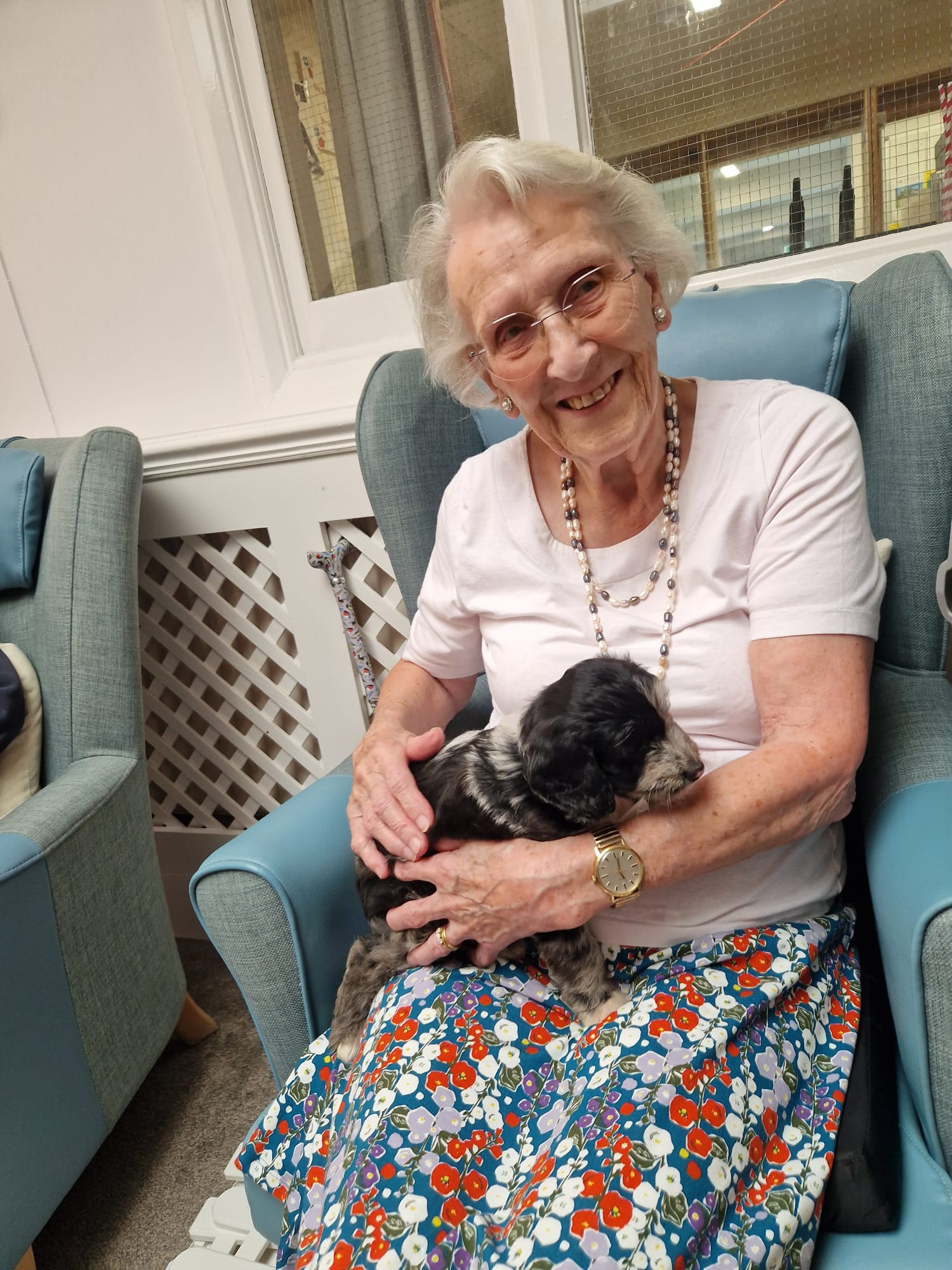 And elderly woman cuddling a puppy and smiling