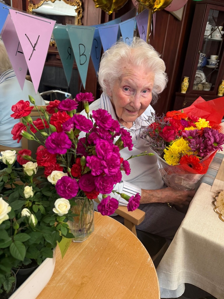 An elderly lady surrounded by bouquets of flowers