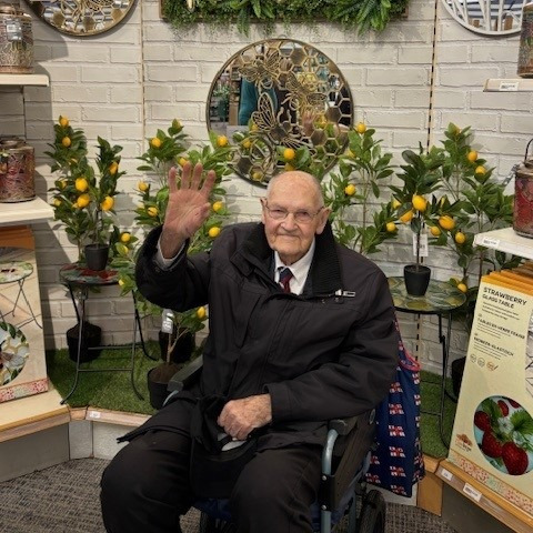 An older gentleman sat in a wheelchair in front of a display in a store
